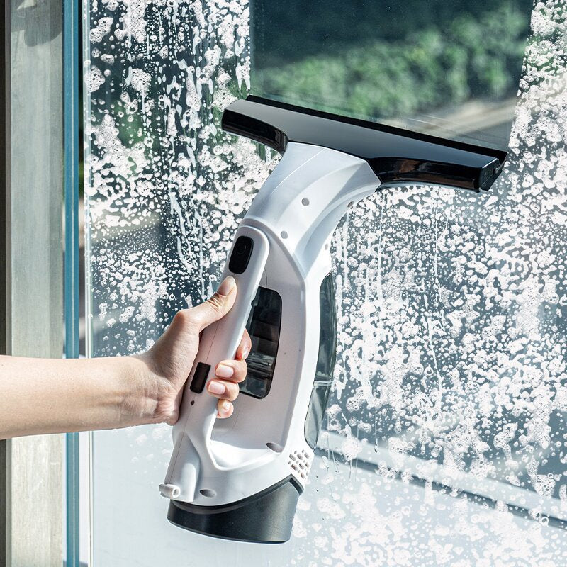 Hand using the ThiccFitts Multifunctional Electric Cordless Window Cleaner Machine to remove soap and clean a glass window.